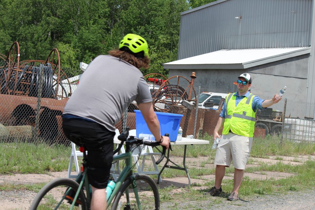 Volunteer Offering Water To Passing Bikers