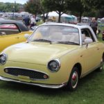 A small yellow 1994 Nissan Figaro at the Classic Car Show for HarborFest