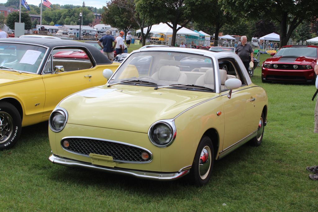 A small yellow 1994 Nissan Figaro at the Classic Car Show for HarborFest